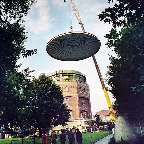 Kran hebt eine vormontierte GFK-Abdecksystem-Kuppel auf einen Wasserturm bei einem Großprojekt